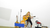 a woman playing an acoustic guitar in a room